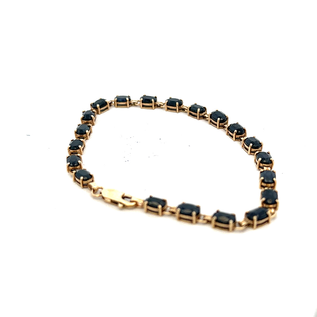 9ct yellow gold sapphire bracelet with silver accents, showcasing a delicate design and sparkling blue sapphires on a fine jewelry piece.