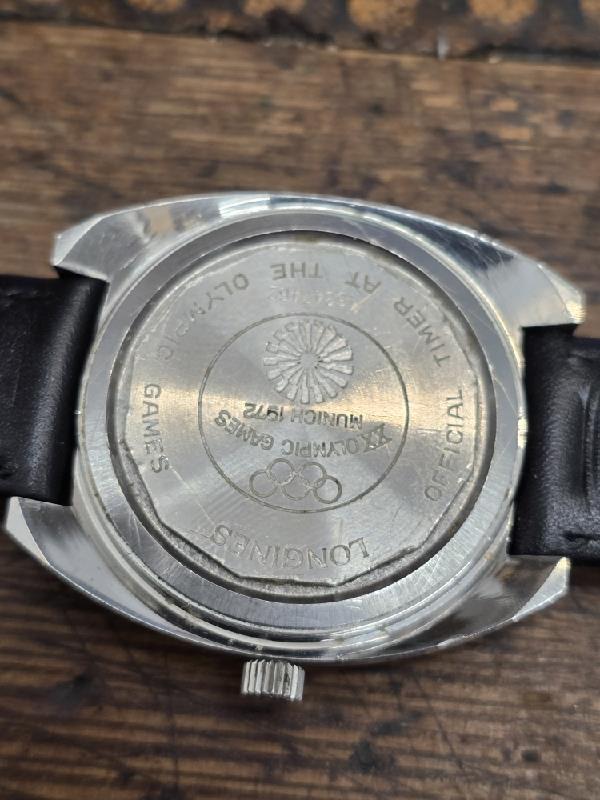 Vintage Longines 1972 Munich Olympics watch with gold-tone case and black leather strap, displaying Olympic logo on dial.