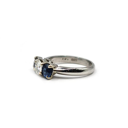 Platinum ring featuring a 1/2 carat diamond and 0.80 carat sapphire gemstone, elegant jewelry piece with detailed design.