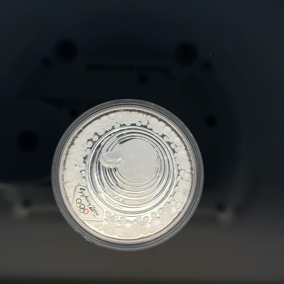 Silver 2000 Olympic coin, 31.4g, unbranded, featuring Olympic design and inscriptions, close-up view showing details and texture.