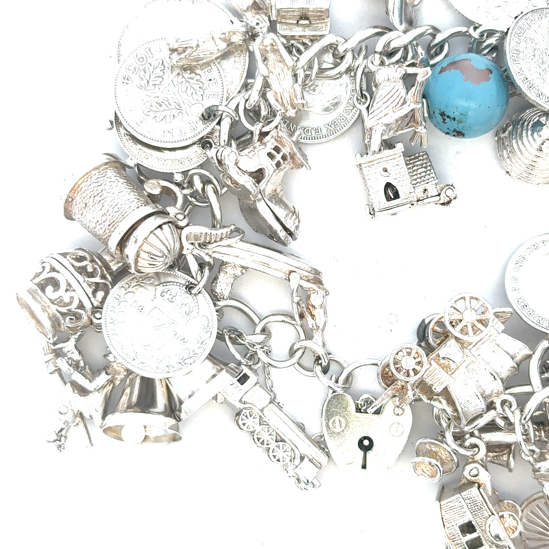 Silver charm bracelet weighing 128.8g with various charms, featuring a sleek design and adjustable chain for stylish wear.