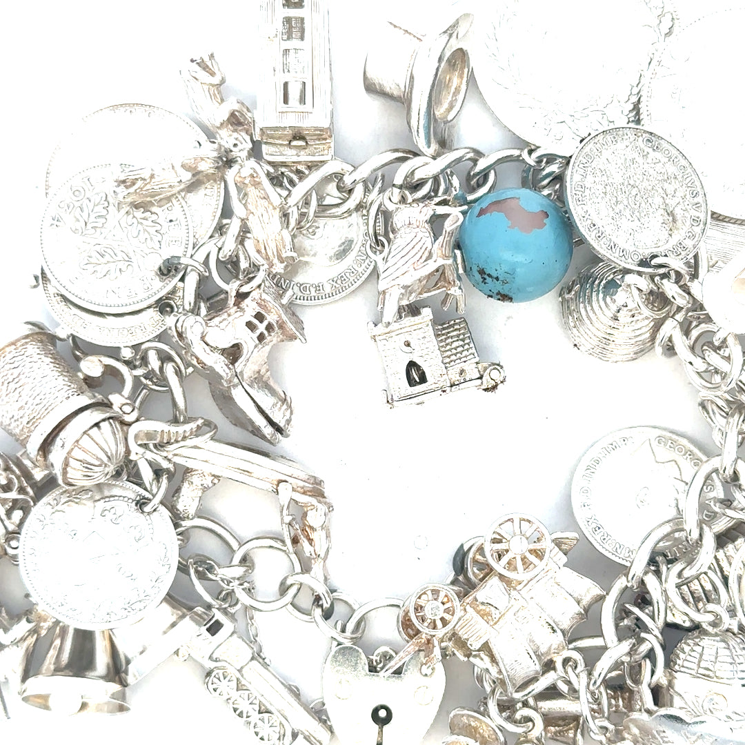 Silver charm bracelet weighing 128.8g with various decorative charms, unbranded jewelry piece on a neutral background.