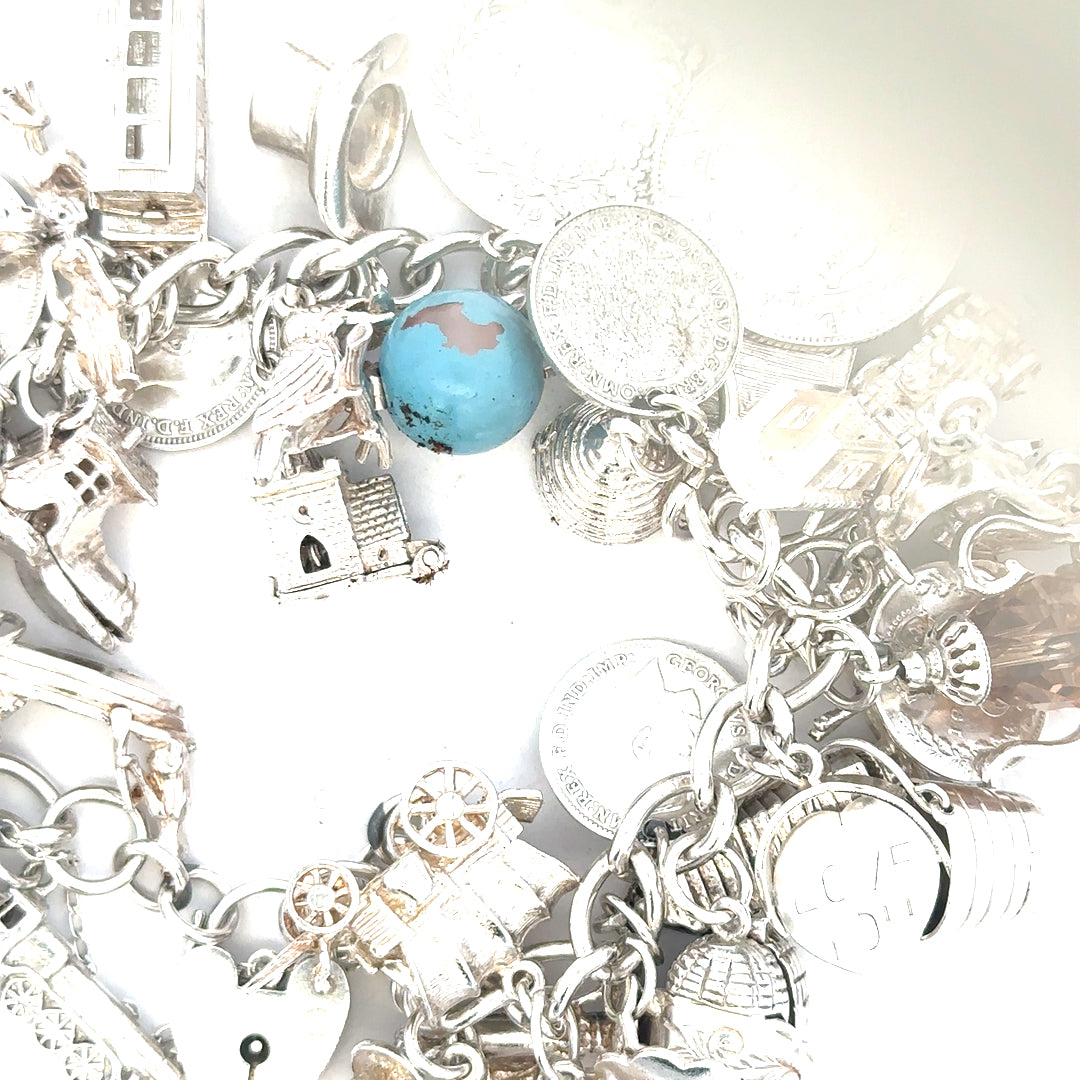 Silver charm bracelet weighing 128.8g with various decorative charms, unbranded jewelry accessory.