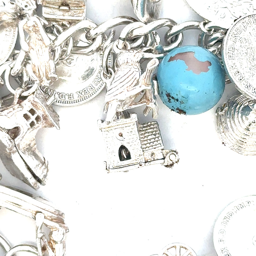 Silver charm bracelet weighing 128.8g with various decorative charms, unbranded, stylish jewelry accessory.