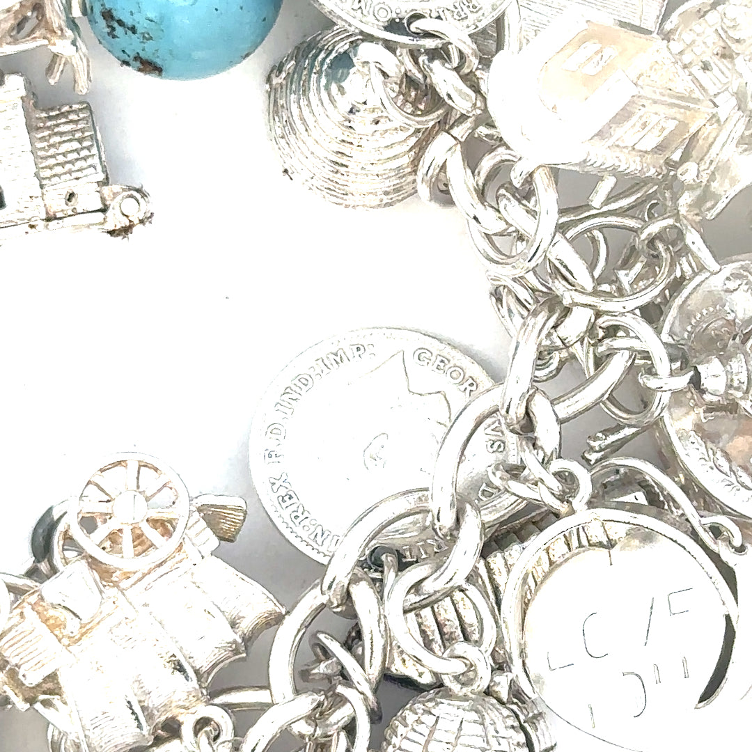 Silver charm bracelet weighing 128.8g with various decorative charms, unbranded jewelry accessory.