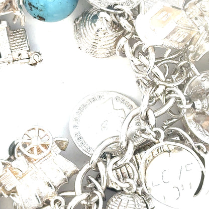 Silver charm bracelet weighing 128.8g with various decorative charms, unbranded jewelry accessory.