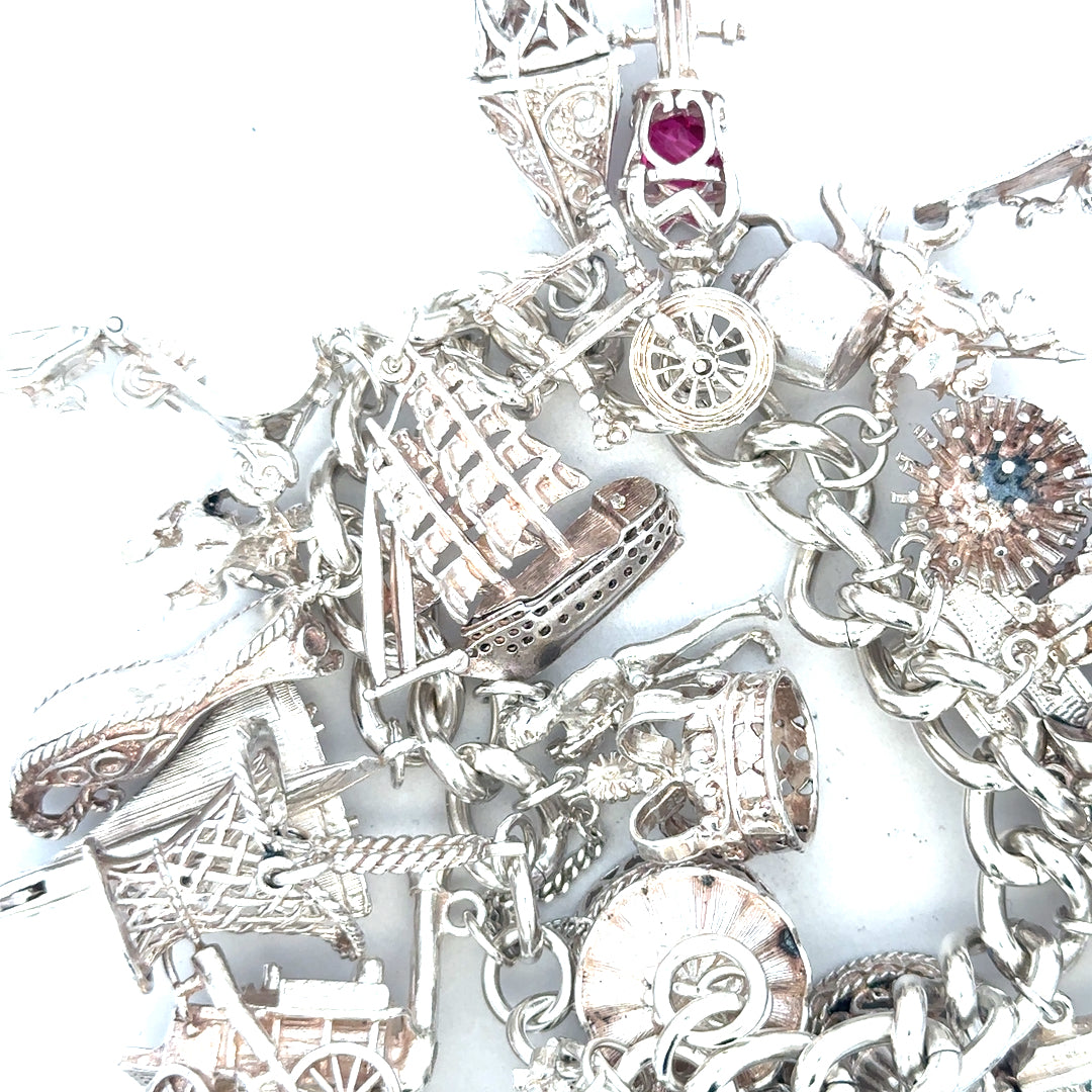 Silver charm bracelet weighing 154.4g with various decorative charms, unbranded jewelry accessory displayed on a neutral background.