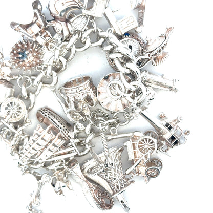 Silver charm bracelet weighing 154.4g with multiple decorative charms, displayed on a neutral background.