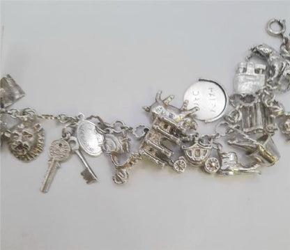 Silver charm bracelet with intricate designs, weighing 45.9g, featuring multiple charms on a sturdy silver chain.