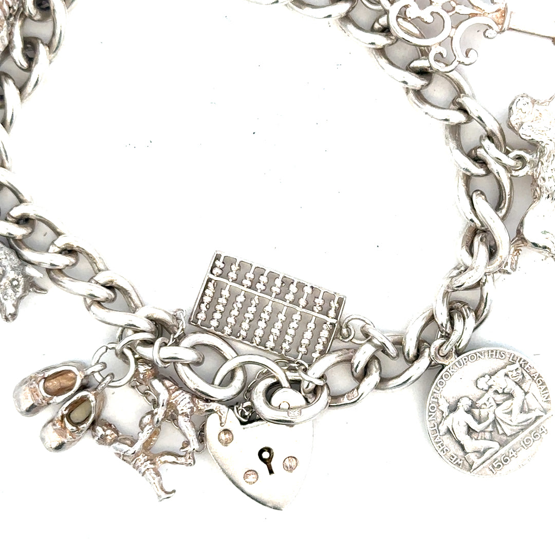 Silver charm bracelet weighs 60.1g with various decorative charms, featuring a sleek unbranded design on a white background.