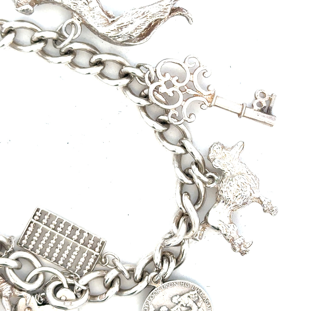 Silver charm bracelet weighing 60.1g, featuring various decorative charms and a secure clasp, unbranded jewelry accessory.