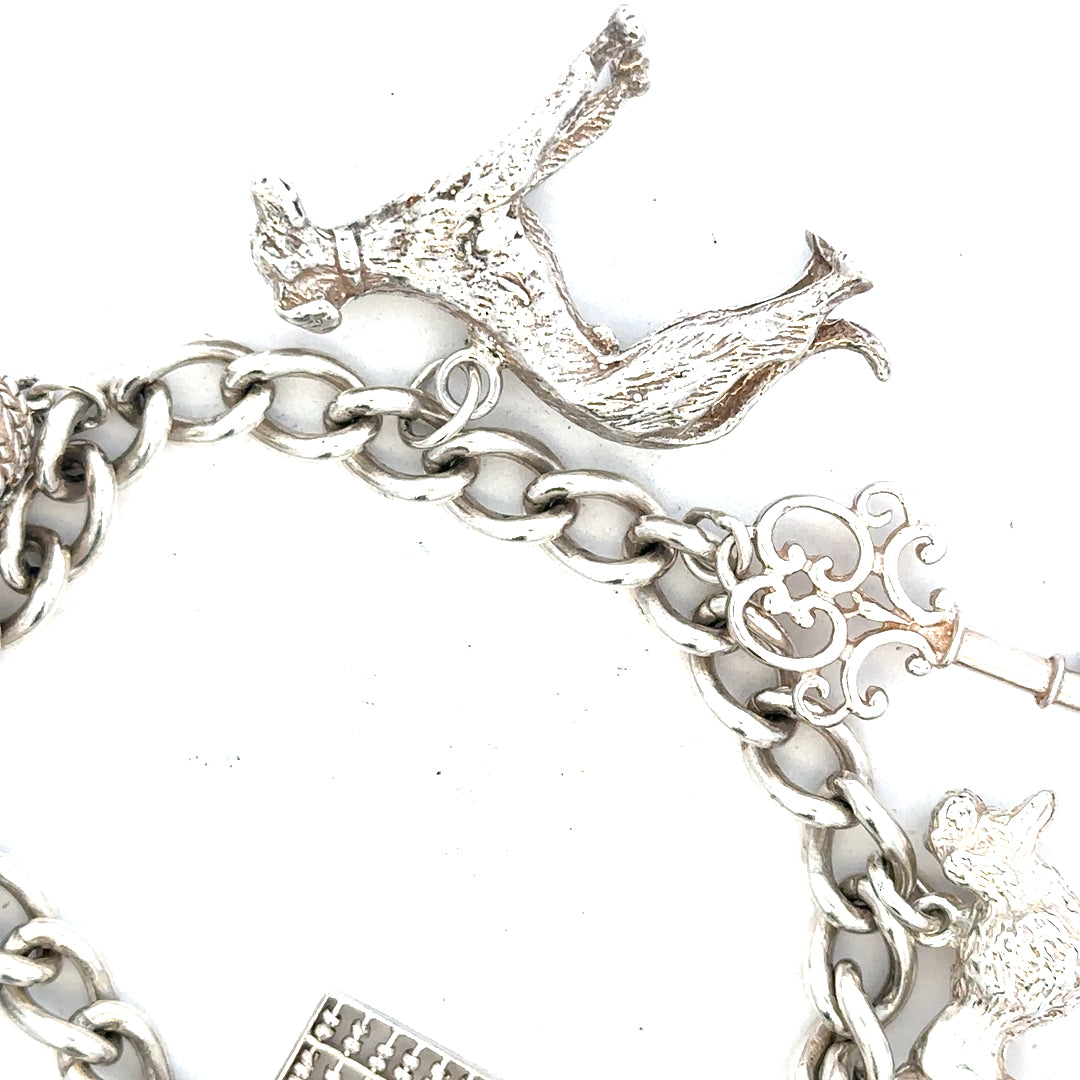 Silver charm bracelet weighing 60.1g, featuring various decorative charms, unbranded jewelry accessory.