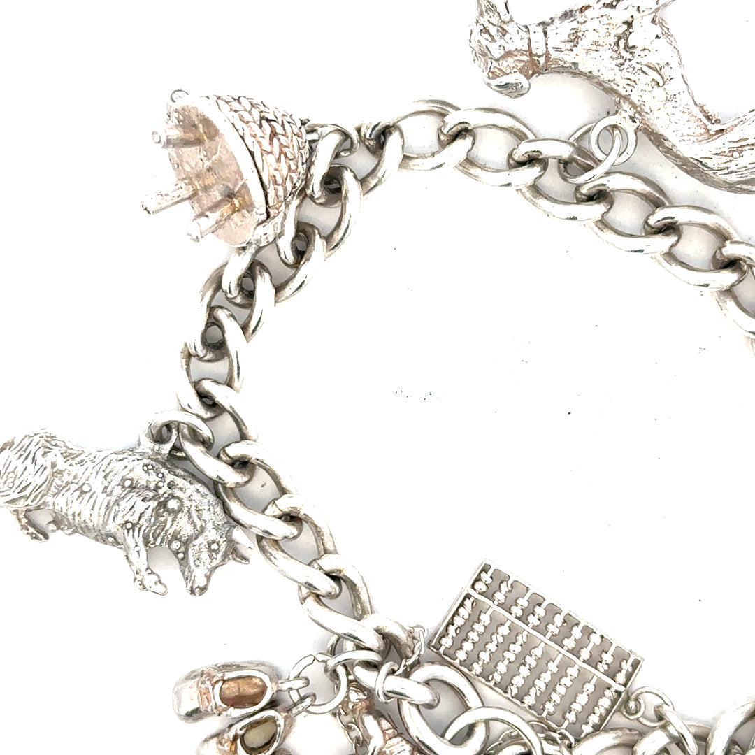 Silver charm bracelet weighing 60.1g with various decorative charms, crafted by an unbranded jewelry maker