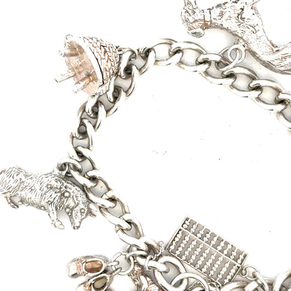 Silver charm bracelet weighing 60.1g with various decorative charms, crafted by an unbranded jewelry maker