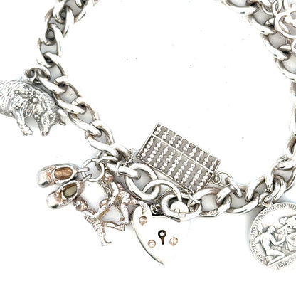 Silver charm bracelet weighing 60.1g with various decorative charms, unbranded jewelry accessory on a plain background.