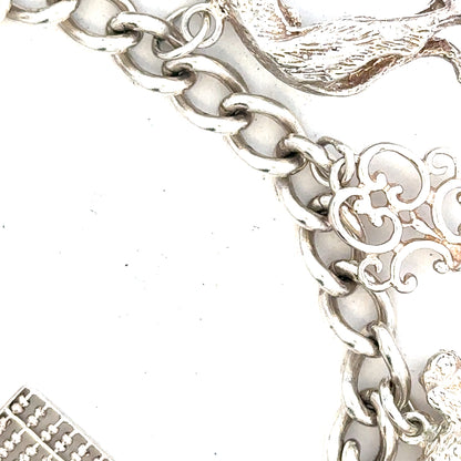 Silver charm bracelet weighing 60.1g with various decorative charms on a neutral background.