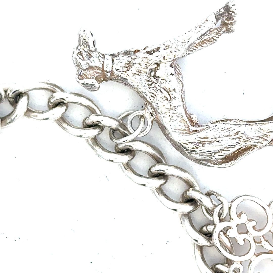 Silver charm bracelet weighing 60.1g with various decorative charms, featuring a secure clasp and polished finish.