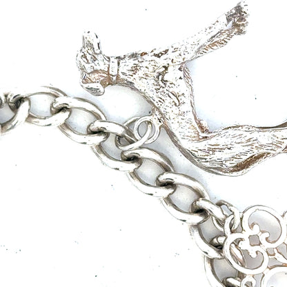 Silver charm bracelet weighing 60.1g with various decorative charms, featuring a secure clasp and polished finish.
