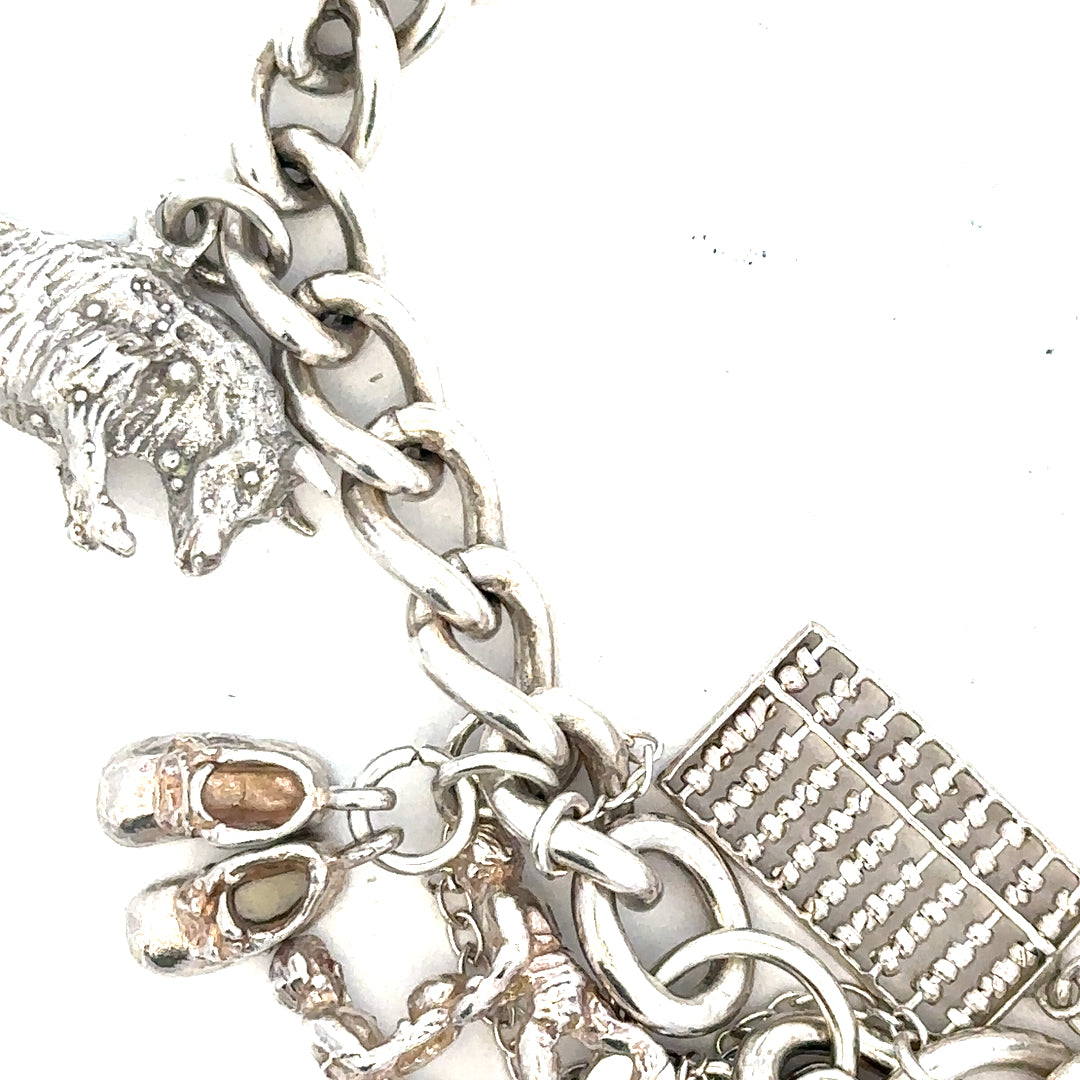 Silver charm bracelet weighing 60.1g with various decorative charms, unbranded jewelry accessory.