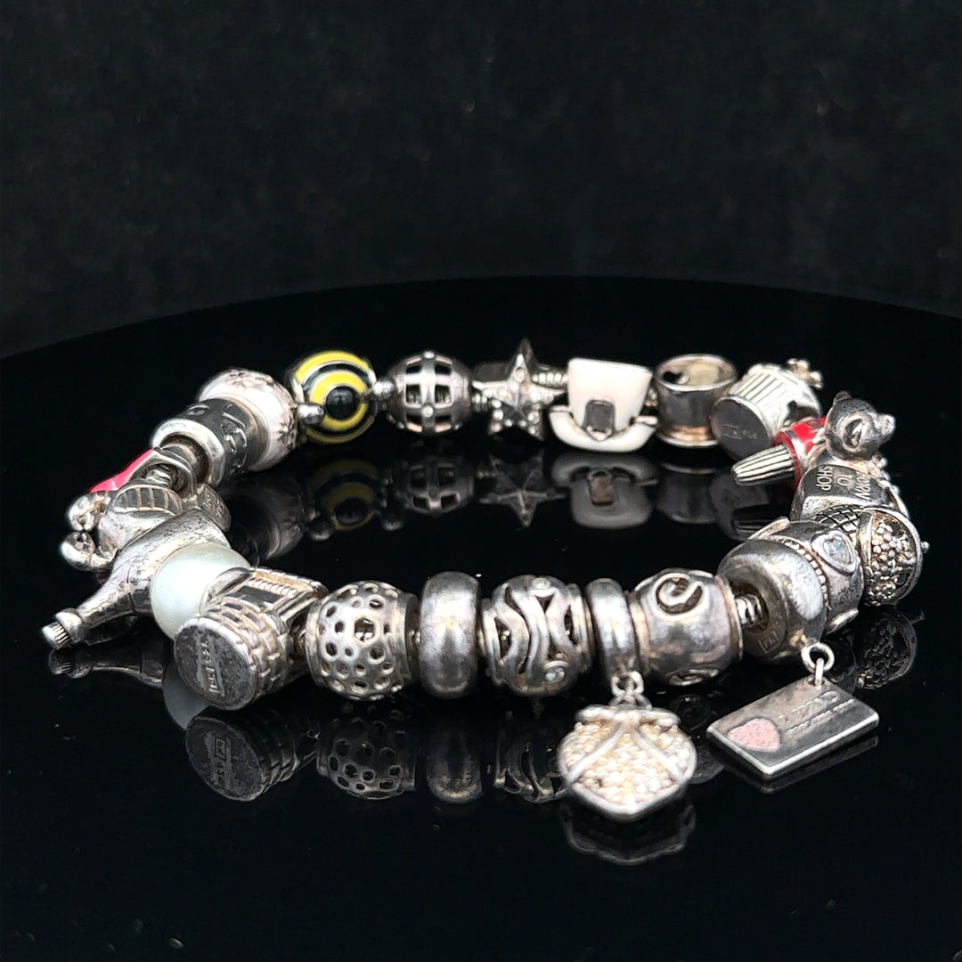 Silver charm bracelet with adjustable length, featuring various decorative charms on a sleek silver chain.