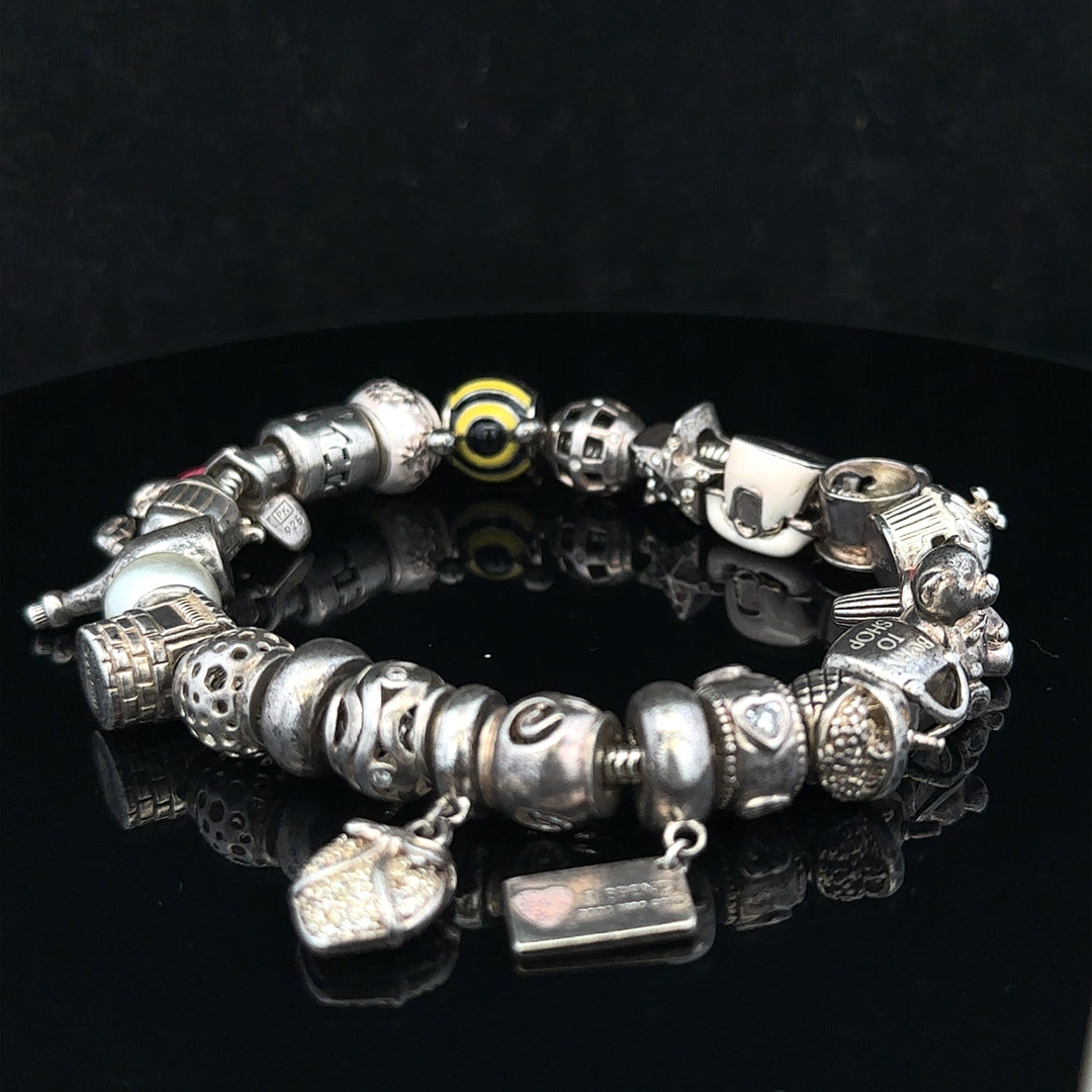Silver charm bracelet with multiple charms, 64.8 cm length, unbranded, shown on a neutral background.