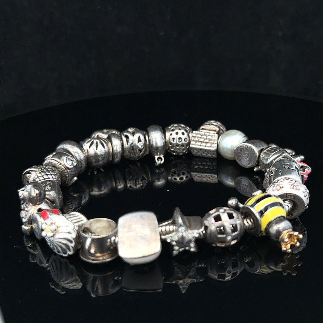 Silver charm bracelet with various charms, 64.8 cm length, unbranded jewelry accessory on a plain background.