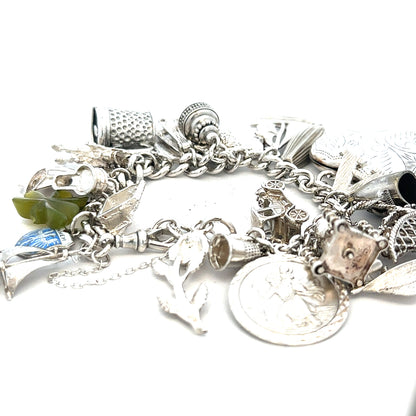 Silver charm bracelet weighing 83.4g with various decorative charms, unbranded jewelry accessory displayed on a neutral background.