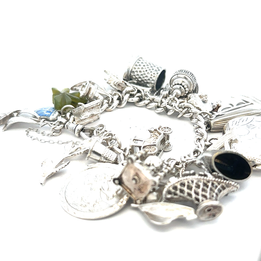 Silver charm bracelet weighing 83.4g with various charms, featuring a sleek design and adjustable clasp, unbranded jewelry accessory.