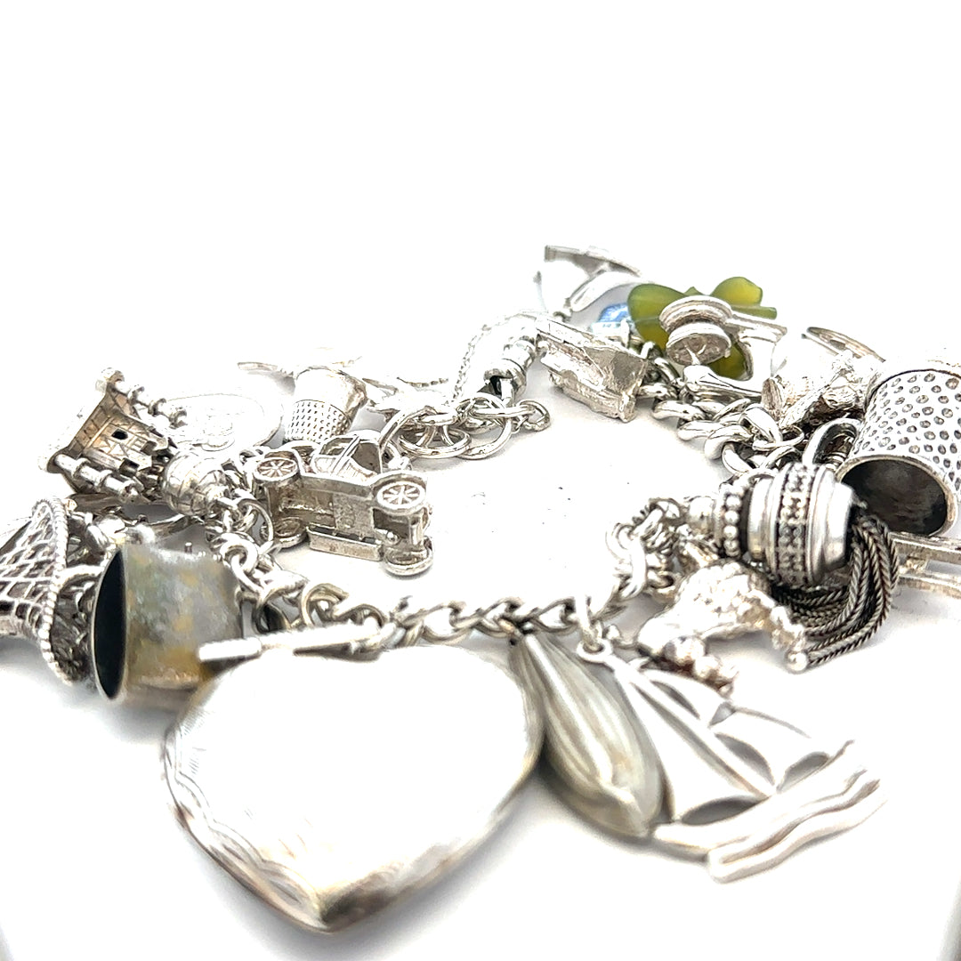 Silver charm bracelet weighing 83.4g with various charms, featuring a sleek unbranded design in a close-up view.
