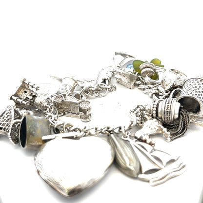Silver charm bracelet weighing 83.4g with various charms, featuring a sleek unbranded design in a close-up view.