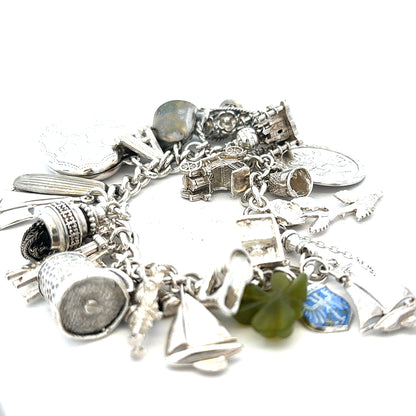 Silver charm bracelet weighing 83.4g with various decorative charms, unbranded jewelry accessory for women