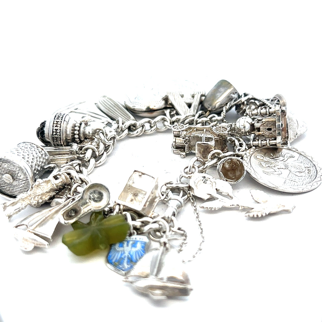 Silver charm bracelet weighing 83.4g with various decorative charms, unbranded, showcasing intricate design and craftsmanship.