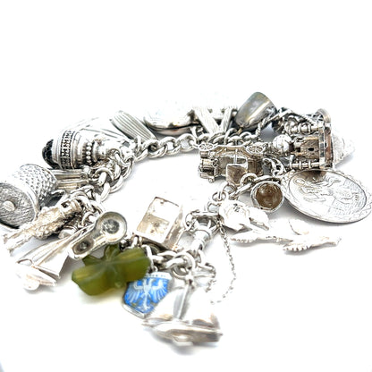 Silver charm bracelet weighing 83.4g with various decorative charms, unbranded, showcasing intricate design and craftsmanship.