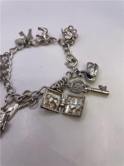 Silver charm bracelet with detailed charms, weighing 33.9g, featuring a stylish and versatile design.