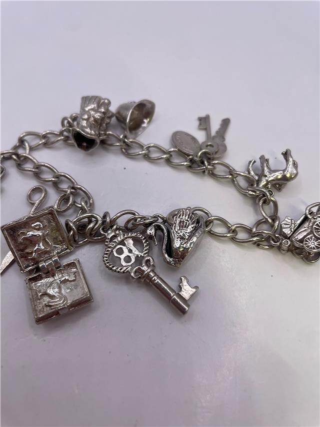 Silver charm bracelet with intricate charms and links, weighing 33.9g, featuring a stylish unbranded design.