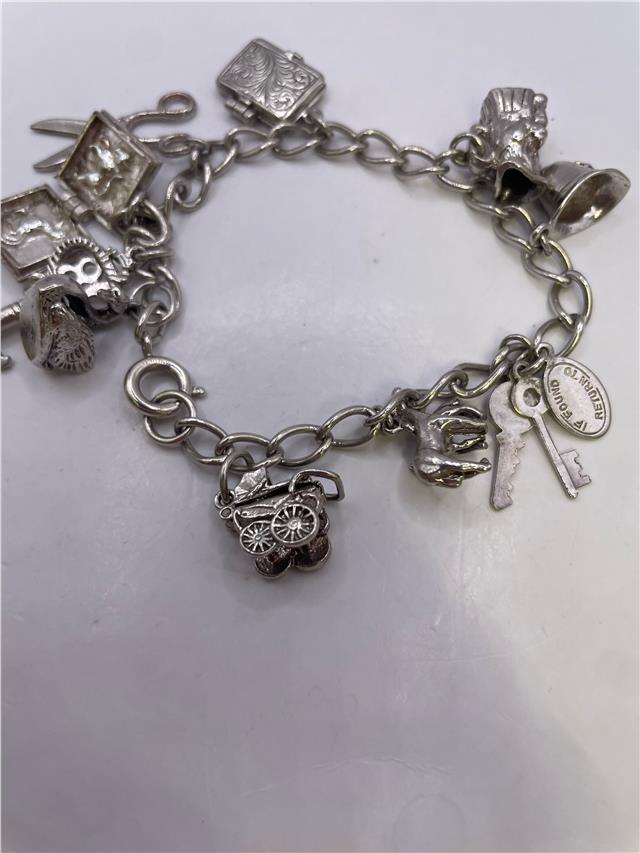 Silver charm bracelet with various charms, weighing 33.9g, featuring intricate details and a secure clasp.