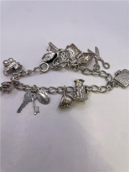 Silver charm bracelet with intricate designs, weighing 33.9g, featuring various charms on a sturdy chain.