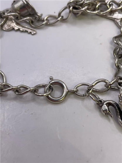 Silver charm bracelet with various charms, weighs 33.9g, unbranded jewelry accessory, detailed close-up of bracelet design