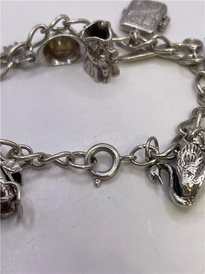 Silver charm bracelet with intricate designs, weighs 33.9g, featuring multiple charms on a durable silver chain.