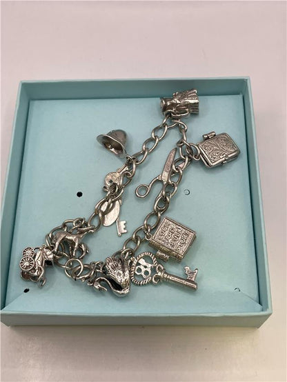 Silver charm bracelet with intricate designs, showcasing its weight of 33.9 grams and detailed charms on a plain background.
