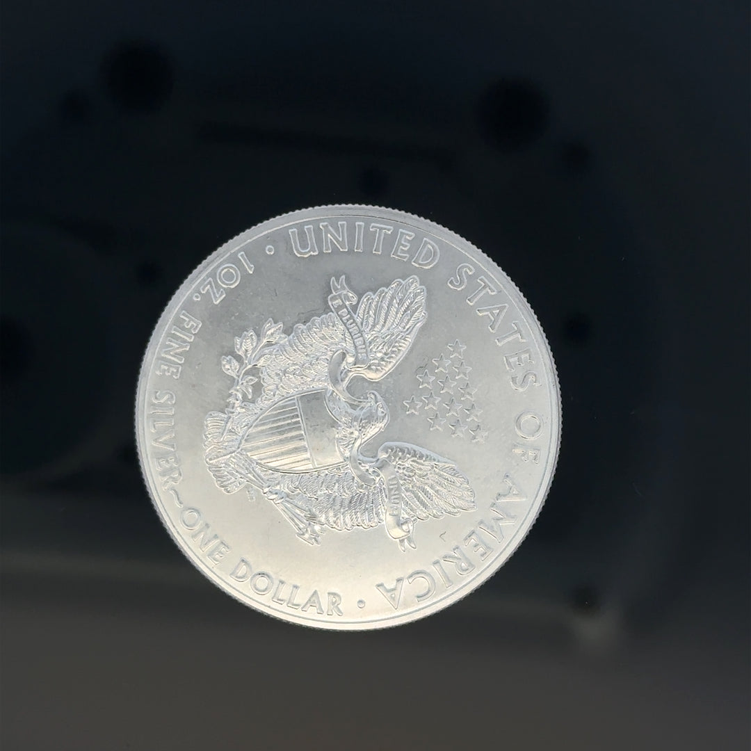 Silver one dollar coin, 31.2g, unbranded, showing detailed design and shiny surface on a plain background.