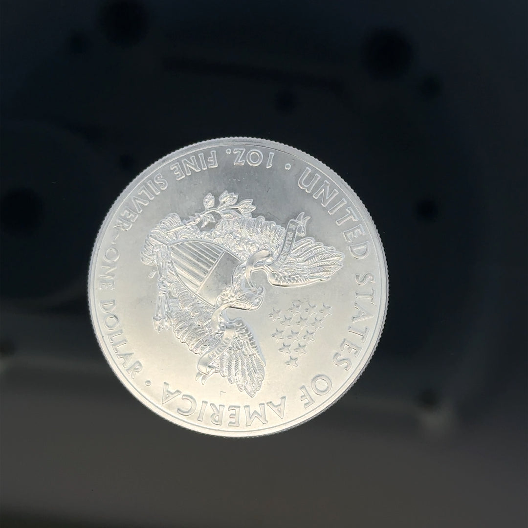 Silver one dollar coin weighing 31.2g, featuring detailed designs and a shiny metallic surface, unbranded collectible currency.