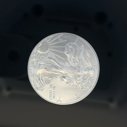 Silver one dollar coin weighing 31.2g, featuring detailed engravings, unbranded, shown from a side view.