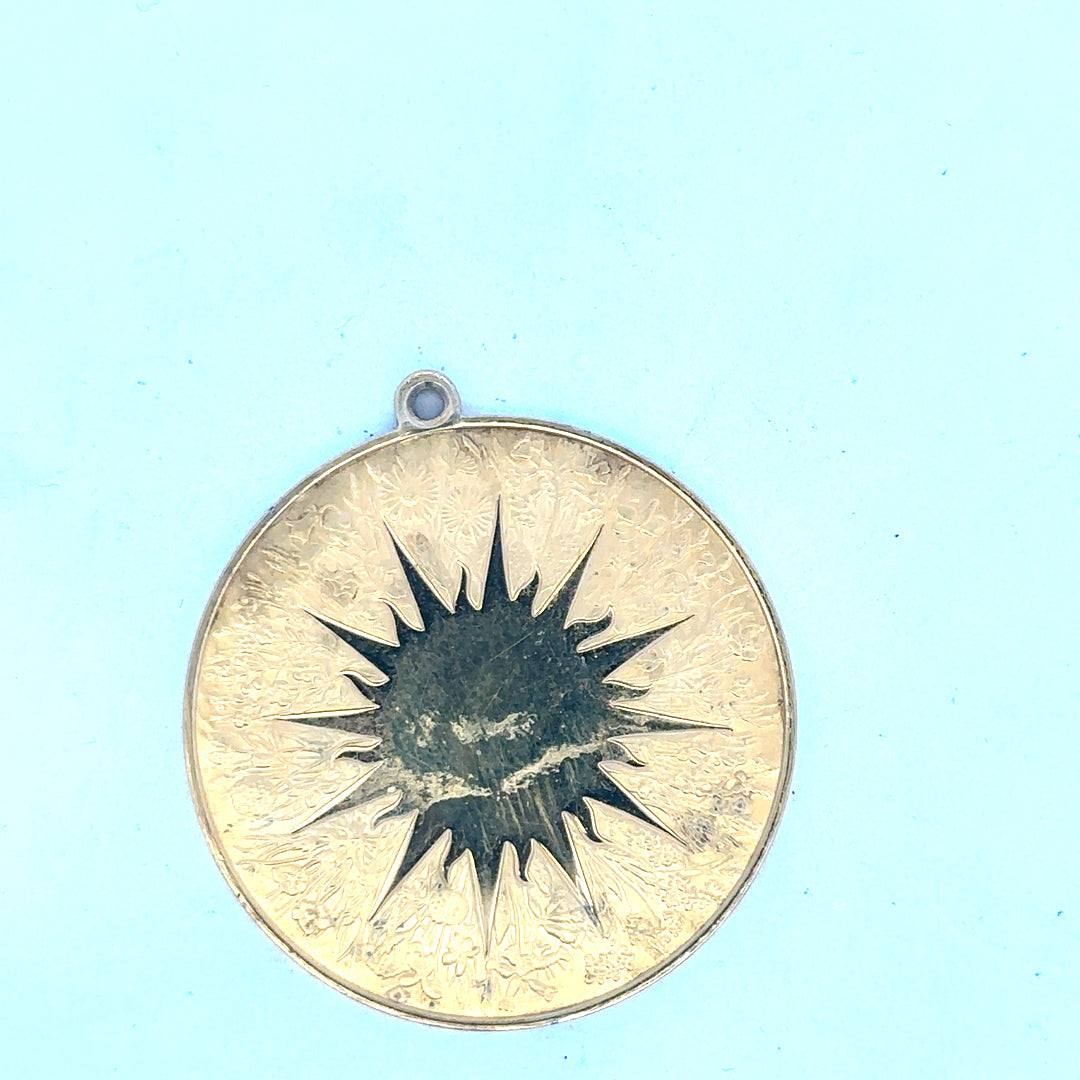 Silver pendant weighing 25.4g with intricate design, showcasing detailed craftsmanship and polished surface.