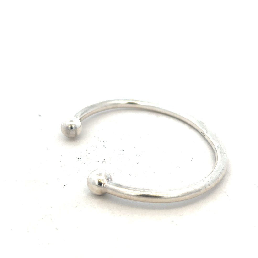 Silver torque bangle in 20g with a smooth, polished finish, featuring a classic unbranded jewelry design.